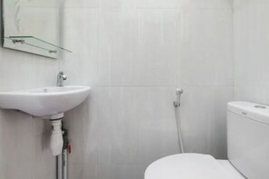 A bathroom with a white sink, a glass shelf, a toilet, and a shower. - OYO 3314 Syariah House (Purwokerto)