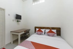 Une chambre d’hôtel avec un lit simple, un bureau et un téléviseur fixé au mur.