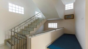 A room with a staircase, a blue carpet, and a framed picture on the wall. - OYO 3314 Syariah House (Purwokerto)