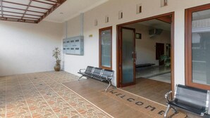 A reception area with a tiled floor, a welcome mat, and two benches. - OYO 3314 Syariah House (Purwokerto)