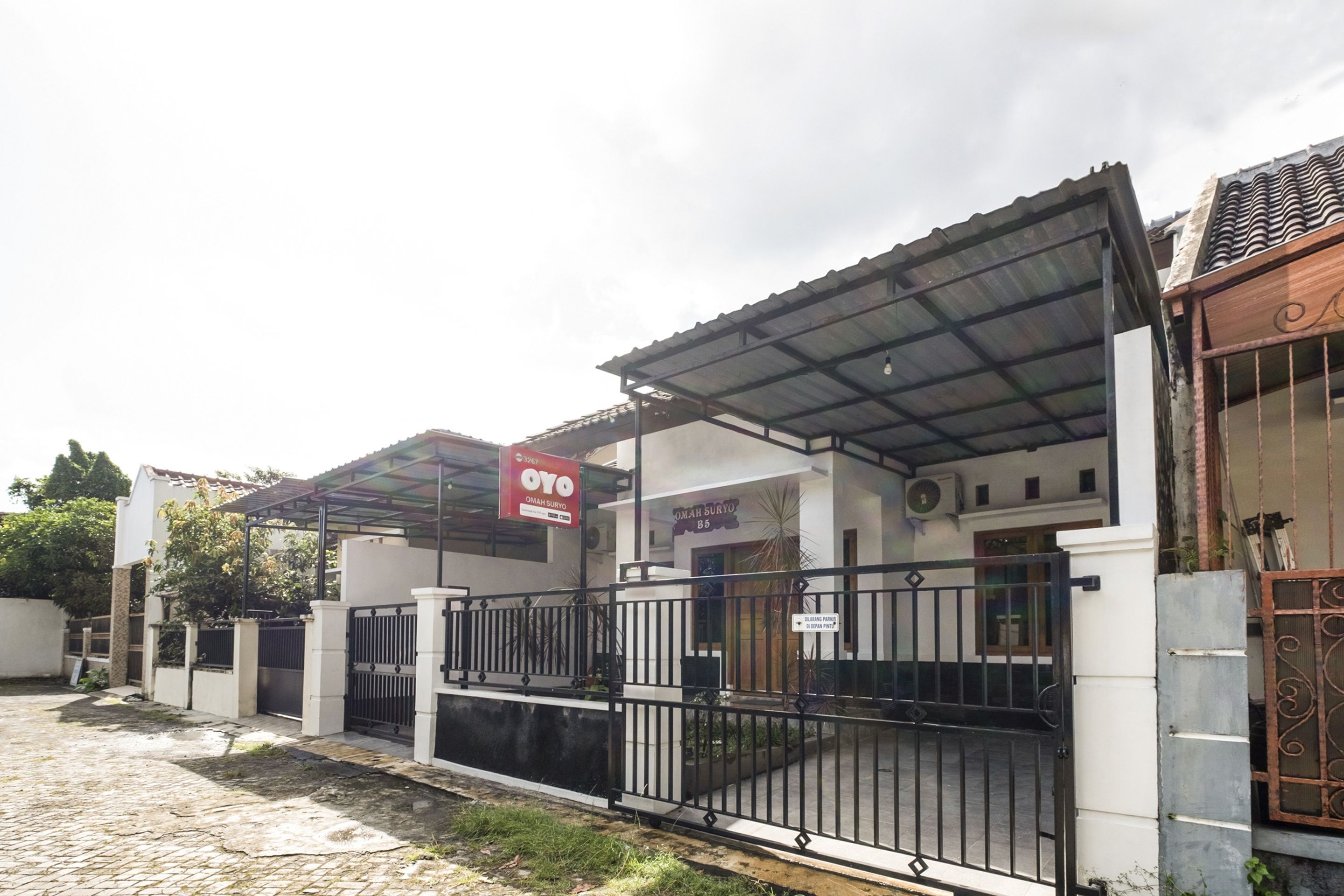 A gated residential area with a covered entrance, a sign for a business, and a building with a tiled roof.