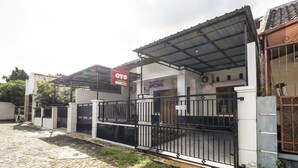 A gated residential area with a covered entrance, a sign for a business, and a building with a tiled roof.