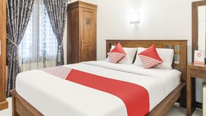 A neatly made bed with a red and white bedspread, a wooden headboard, and two red pillows with white text.