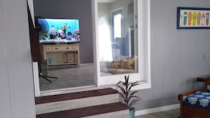 Una sala de estar con televisor, planta y cama.