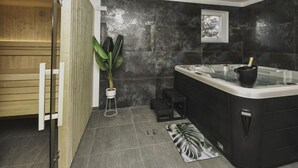 Ein modernes Badezimmer mit Sauna, einer großen schwarzen Badewanne und einem Blumentopf.
