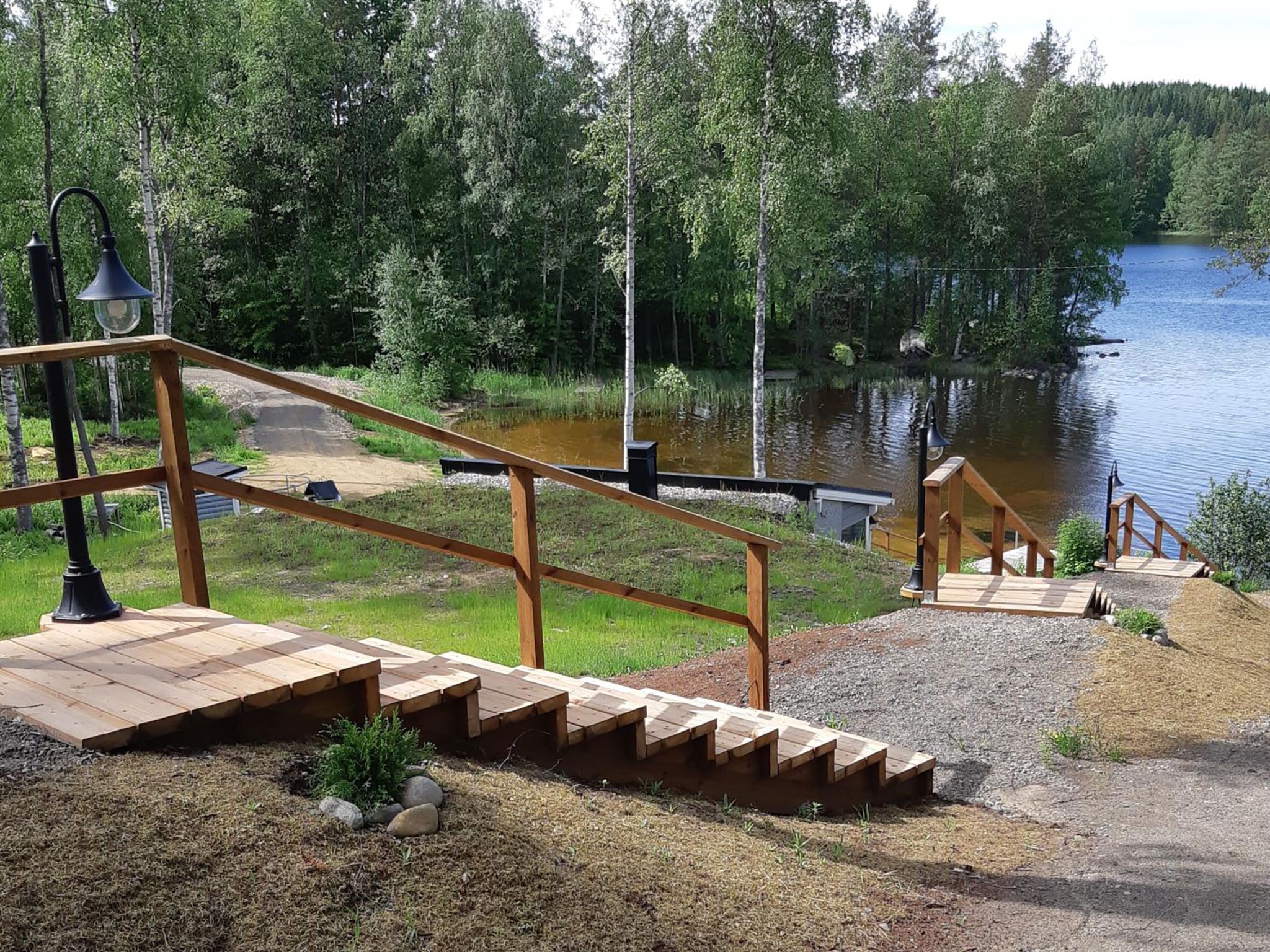 A wooden staircase leading to a dock over a calm lake, surrounded by dense forest.