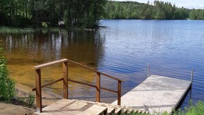 Un muelle de madera se adentra en un lago tranquilo rodeado de un bosque denso.