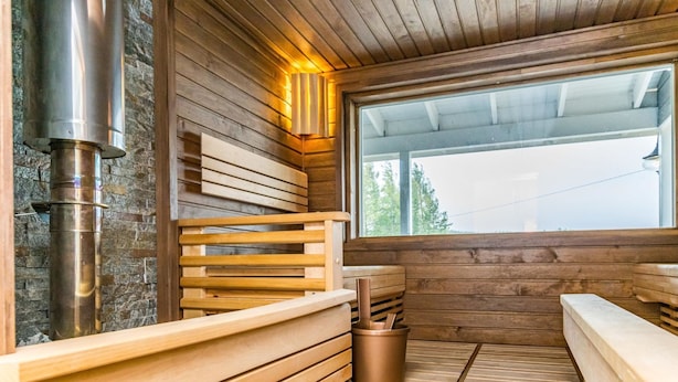 Una sauna con bancos de madera, pared de piedra y un ventanal grande.