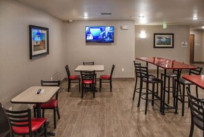 Um restaurante com mesas e cadeiras, uma televisão presa na parede e quadros decorando as paredes.