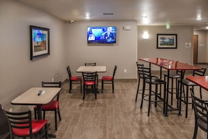 A restaurant with tables and chairs, a television mounted on the wall, and framed pictures on the walls.