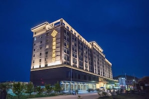 A multi-story hotel building with illuminated signage, a flat facade, and a ground-level entrance. - Wonderful Hotel (Huidong)