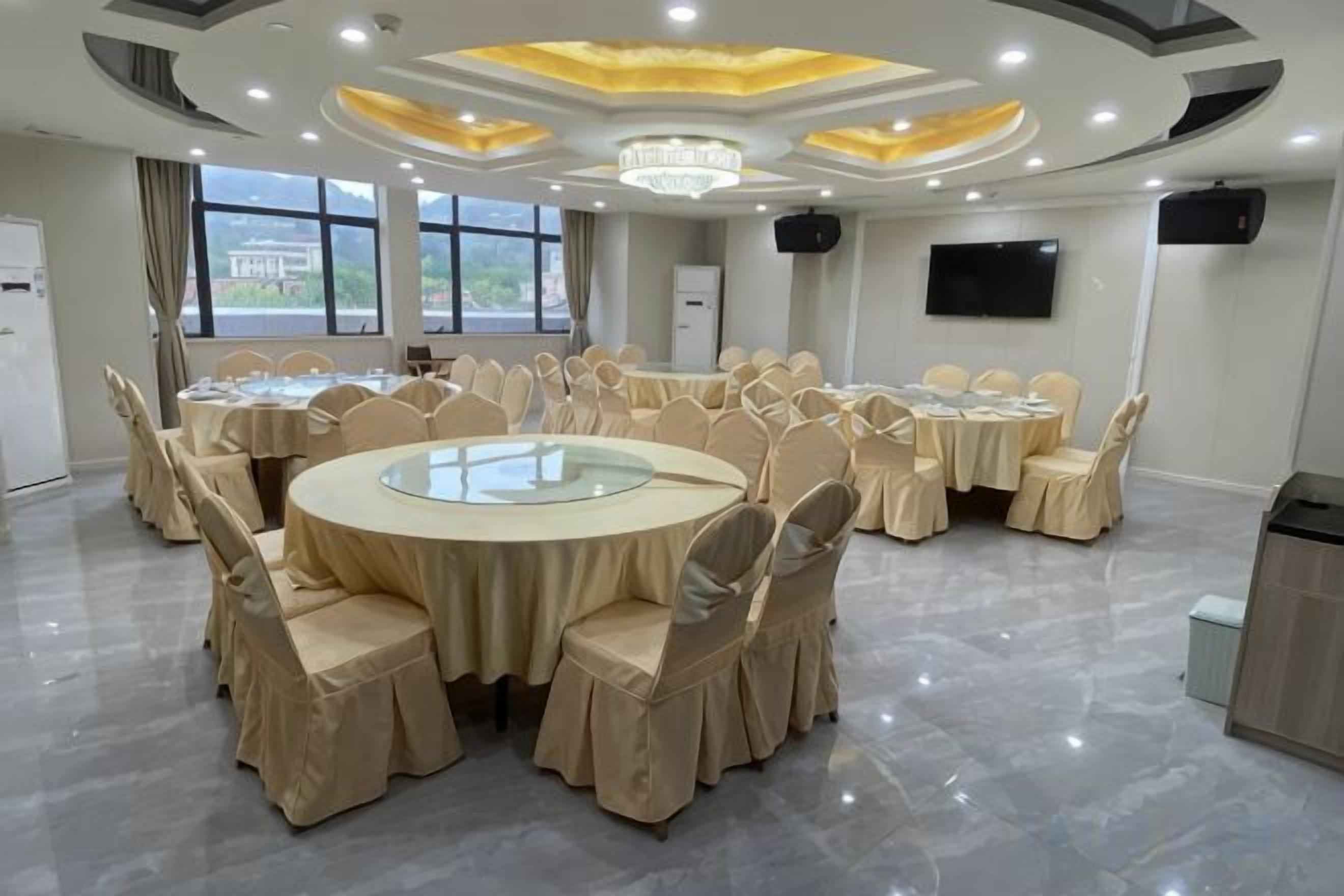 Un salón de conferencias con mesas redondas, sillas y una pantalla grande.