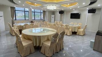 Un salón de conferencias con mesas redondas, sillas y una pantalla grande.