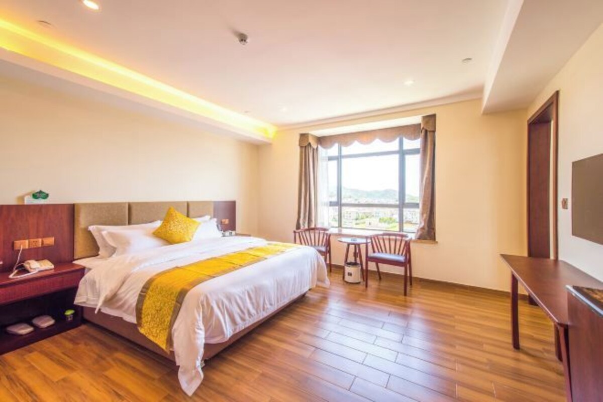 A hotel room with a large bed, a desk, and a chair.