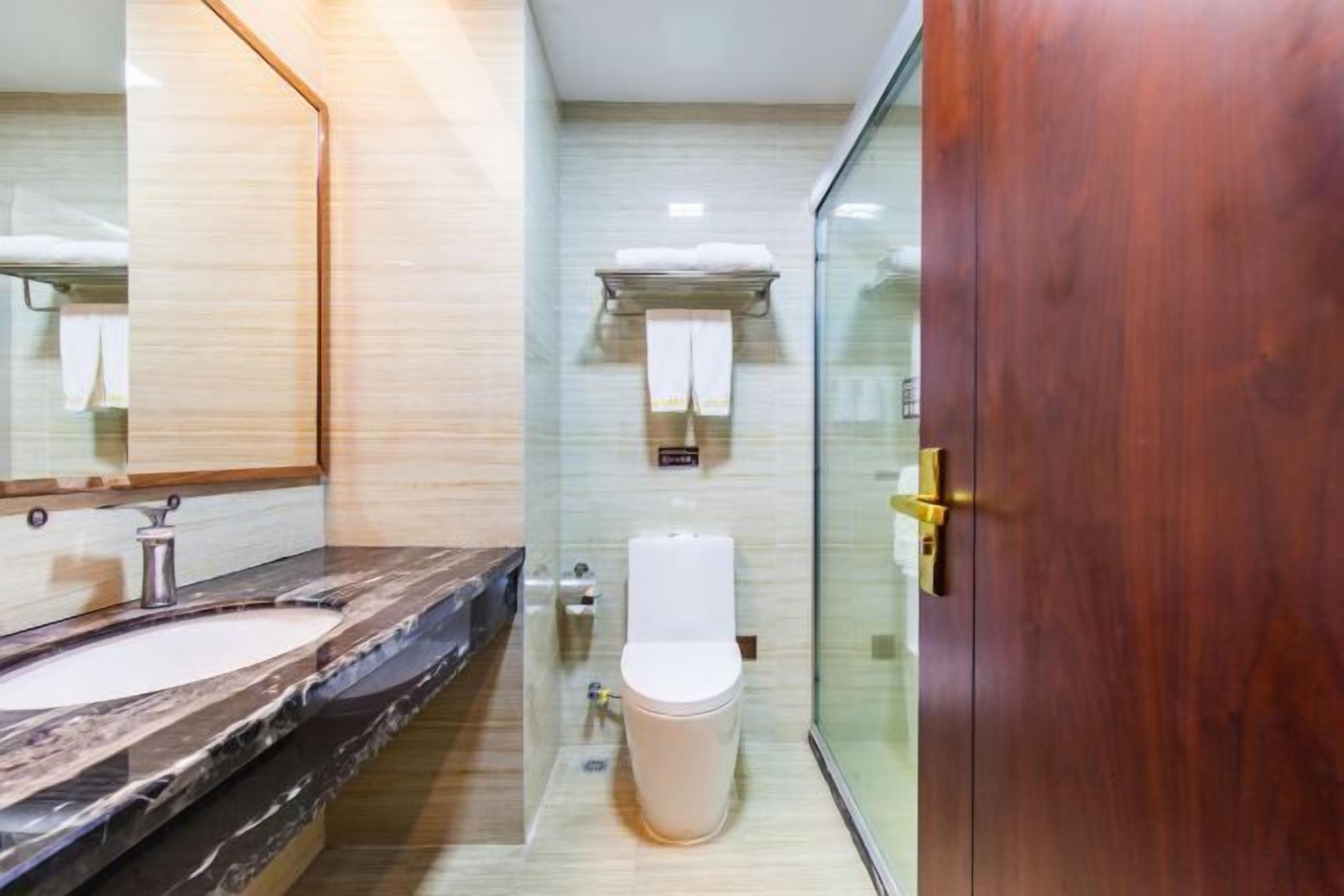A modern bathroom with a marble sink, a toilet, and a glass shower enclosure.