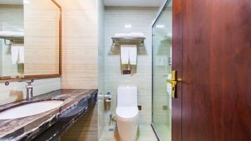 A modern bathroom with a marble sink, a toilet, and a glass shower enclosure.