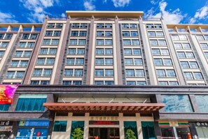 Um hotel com vários andares, entrada destacada e fachada envidraçada.