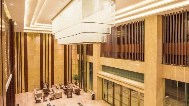 A spacious lobby with a high ceiling, a large chandelier, and a seating area with sofas and chairs. - Wonderful Hotel (Huidong)