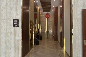 A marble hallway with a directional sign, a red circular decoration, and a fire extinguisher.