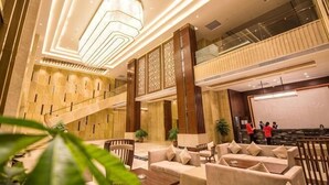 A lobby with a staircase, seating area, and a large screen. - Wonderful Hotel (Huidong)