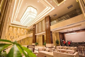 Eine Lobby mit Treppe, Sitzgelegenheiten und einem großen Bildschirm.