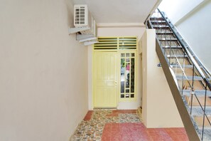A staircase leading to a yellow door with a vent above it. - OYO 3252 Lansano Residence (Padang)