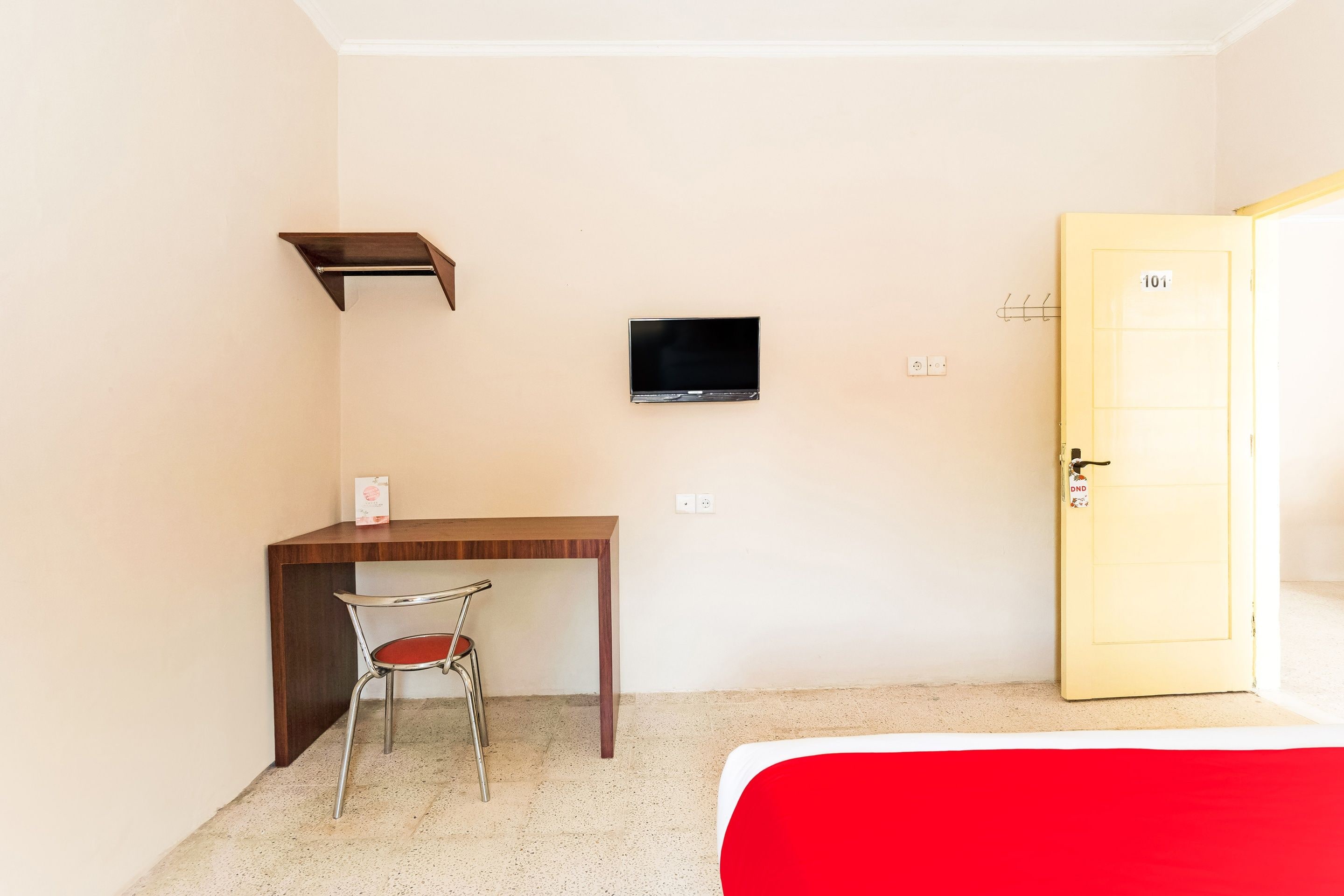 A small room with a desk, chair, TV, and a door.