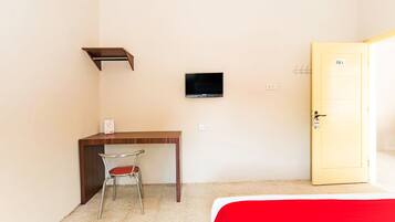 A small room with a desk, chair, TV, and a door.