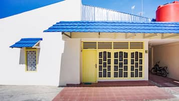 A building with a yellow door, a blue roof, and a red water tank.