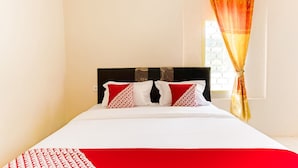 A neatly made bed with a white and red bedspread, two patterned pillows, and a dark headboard. - OYO 3252 Lansano Residence (Padang)