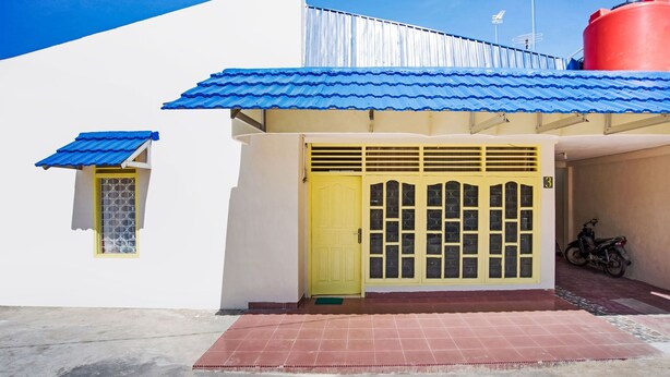A building with a yellow door, a blue roof, and a red water tank. - OYO 3252 Lansano Residence (Padang)