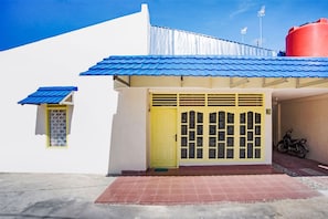 A building with a yellow door, a blue roof, and a red water tank.