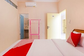 A hotel room with a bed, a pink chair, and a door labeled "104". - OYO 3252 Lansano Residence (Padang)