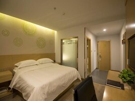 Una habitación de hotel con cama, mesita de noche y escritorio con silla.