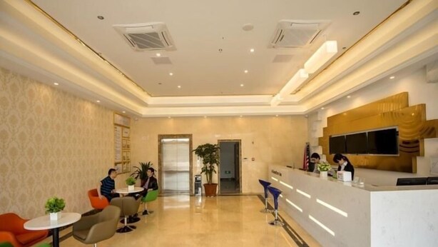 A modern hotel lobby with a reception desk, seating area with colorful chairs, and a large plant. - Greentree Inn Danyang Danbei Town Xinqiao (Zhenjiang)