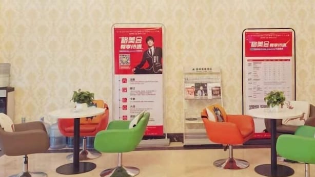 A hotel lobby with modern chairs, small tables, and informational posters on the walls.
