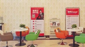 A hotel lobby with modern chairs, small tables, and informational posters on the walls.