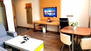 A modern living room with a sofa, a coffee table, a TV, and a dining area with a table and chairs.