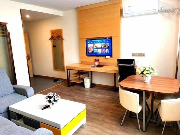 A modern living room with a sofa, a coffee table, a TV, and a dining area with a table and chairs. - Greentree Inn Danyang Danbei Town Xinqiao (Zhenjiang)