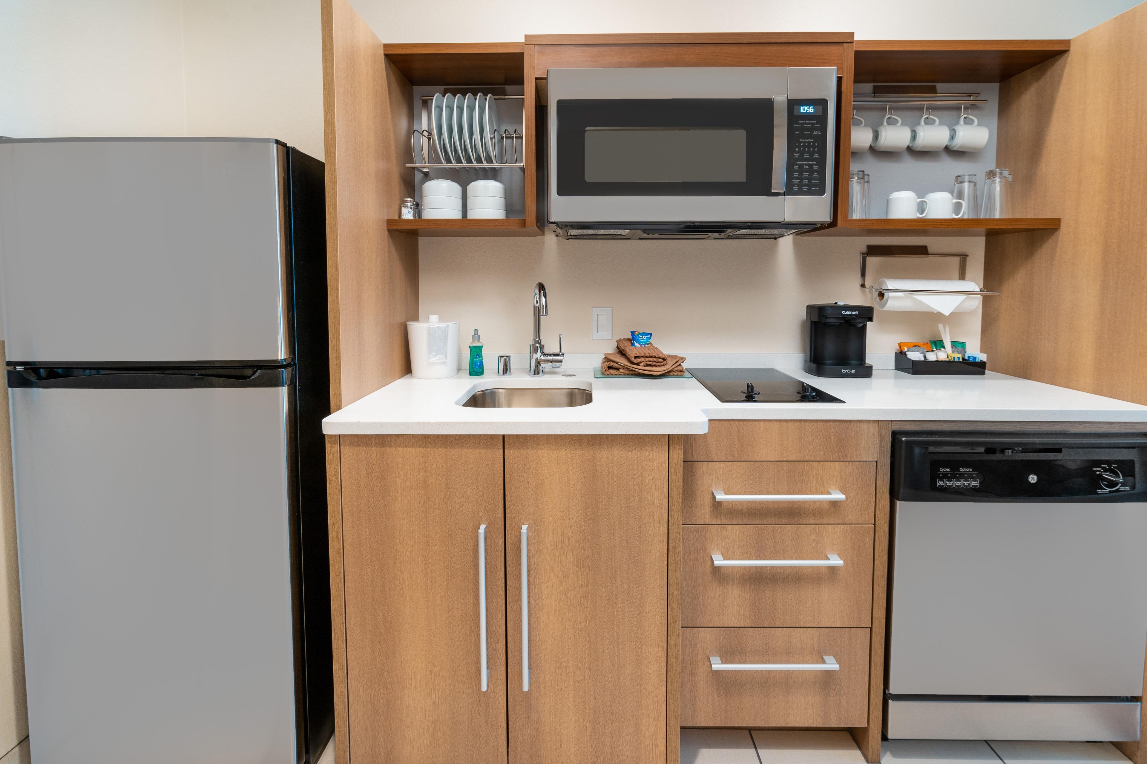 A compact kitchen with a refrigerator, microwave, coffee maker, and dishwasher.