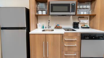 A compact kitchen with a refrigerator, microwave, coffee maker, and dishwasher.