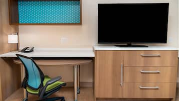 A modern office space with a desk, chair, TV, and storage cabinet.