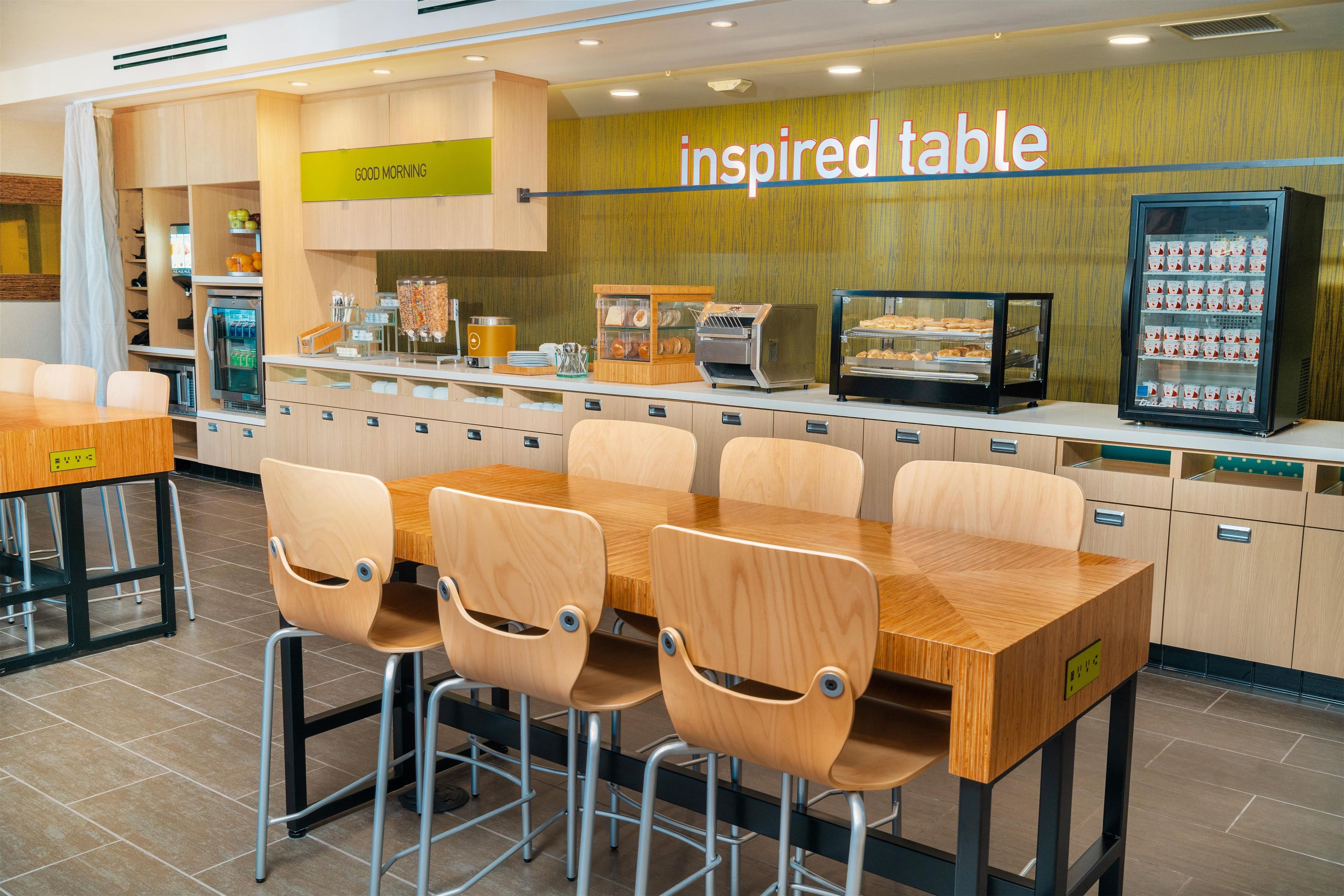 A restaurant with a breakfast counter, a vending machine, and a sign that reads 'inspired table'.
