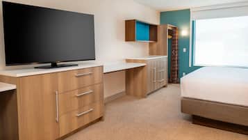 A modern hotel room with a flat-screen TV, wooden furniture, a bed, and a window.