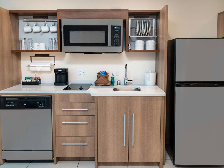 Uma cozinha moderna equipada com micro-ondas, máquina de café e lava-louças.