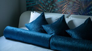 A bed with blue pillows and a patterned wall behind it. - Design Hotel Blax (Hachioji)