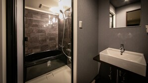 A modern bathroom with a glass-enclosed shower, a white sink, and a mirror above it. - Design Hotel Blax (Hachioji)