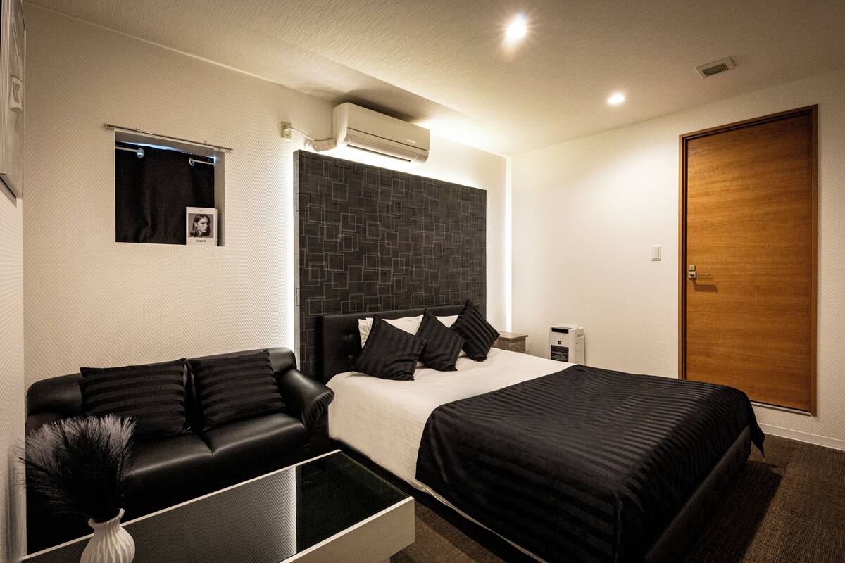 Ein modernes Hotelzimmer mit Bett, einer Couch, einem kleinen Tisch und einem Nachttisch.