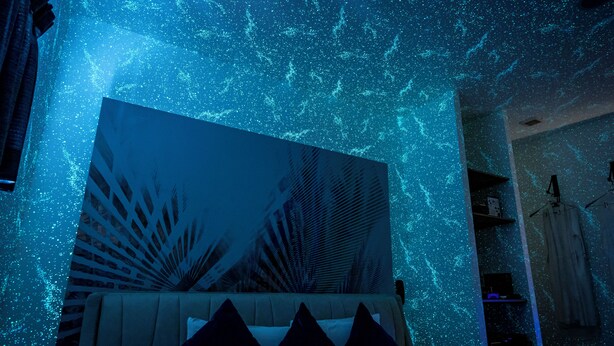 A room with a bed, a large abstract painting, and a starry ceiling effect. - Design Hotel Blax (Hachioji)