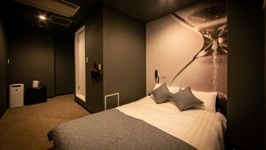 A modern hotel room with a large bed, a nightstand, a wall-mounted phone, and a small bedside table. - Design Hotel Blax (Hachioji)